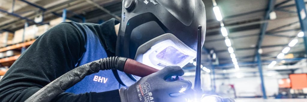 Welder in a welding helmet TIG welding on a welding table in the production hall