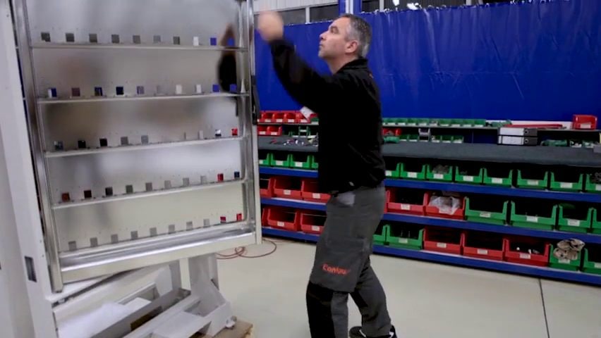 Medewerker bij een kantelbaar rek met roestvaststalen plaat en gemonteerde onderdelen in de assemblagehal