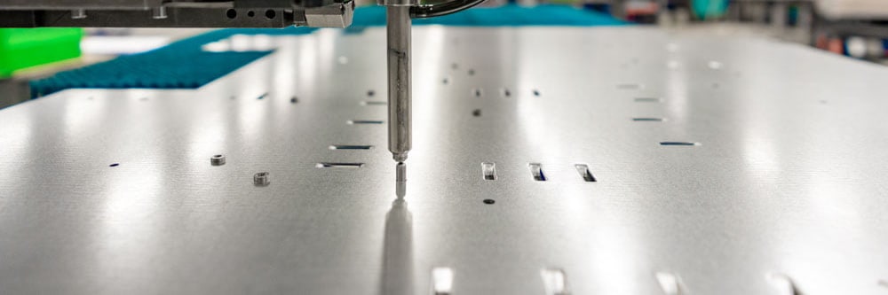Pem inserting head pressing a self-clinching nut into a sheet metal plate with holes and slots