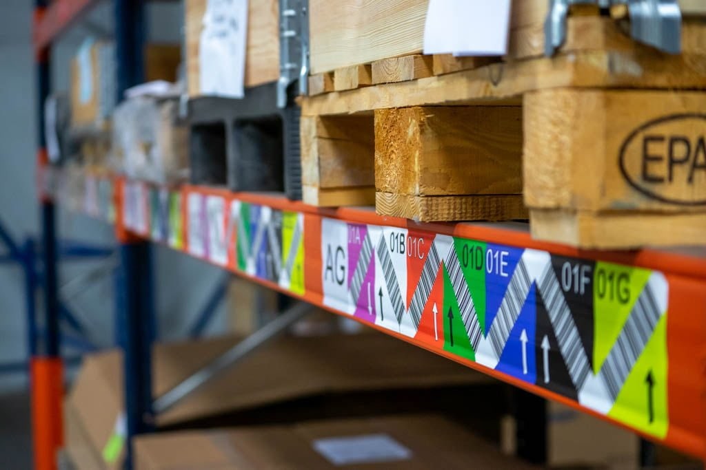 Racking with colour-coded barcode labels per bay and pallets, used for logistics and production control