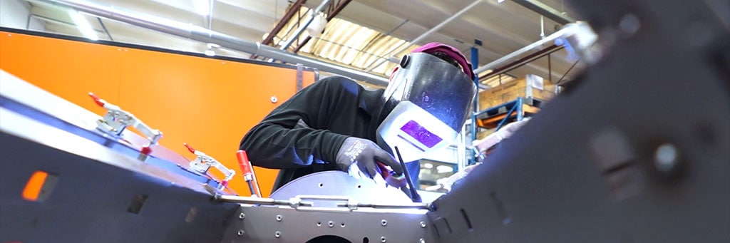 Welder with helmet welding on a rolled sheet metal structure with cut-outs