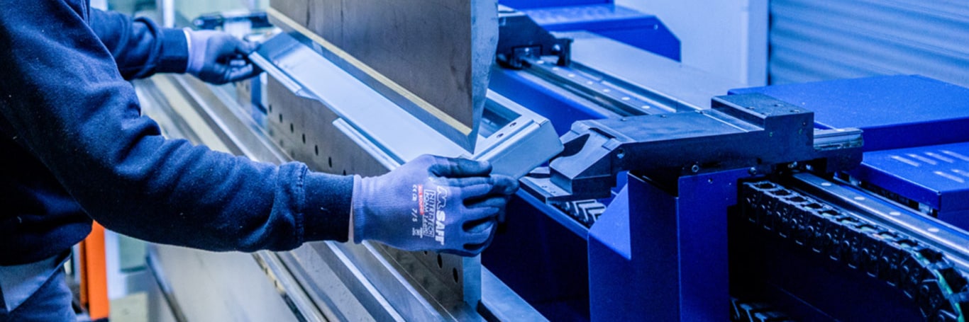Employee’s hands placing a sheet metal part in a press brake