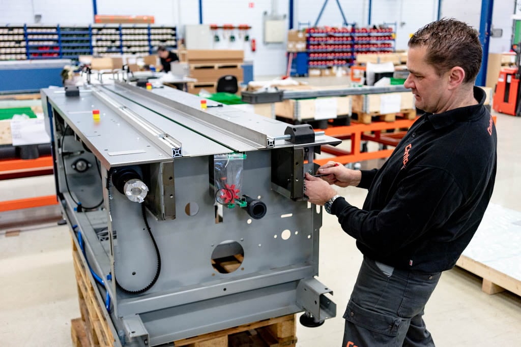 Monteur van Contour monteert een onderdeel aan een metalen frame op een pallet in de montagehal