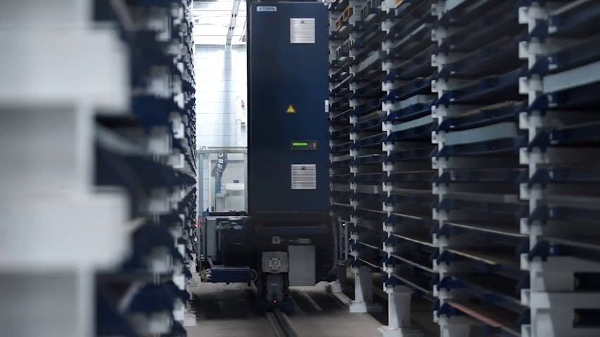 Automated sheet metal store with tall racks left and right and a blue storage crane in the middle