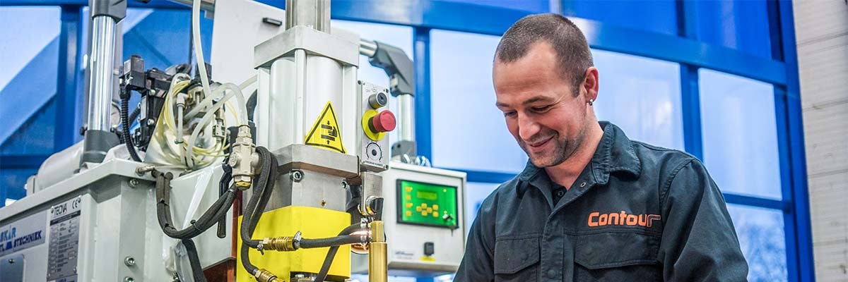Smiling employee operating a spot welding machine