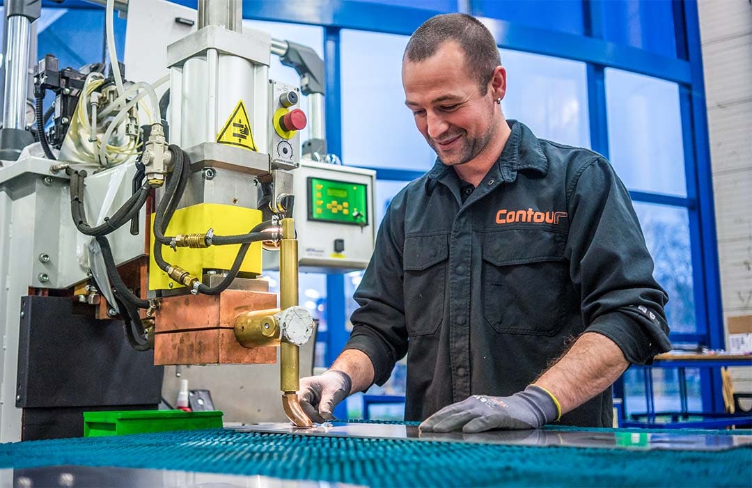 Lachende medewerker bedient een puntlasmachine