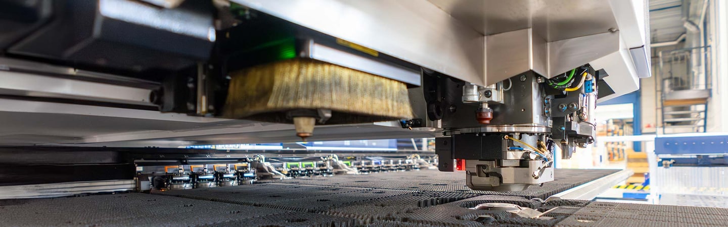 Punching head of a CNC punching machine above a sheet on the worktable
