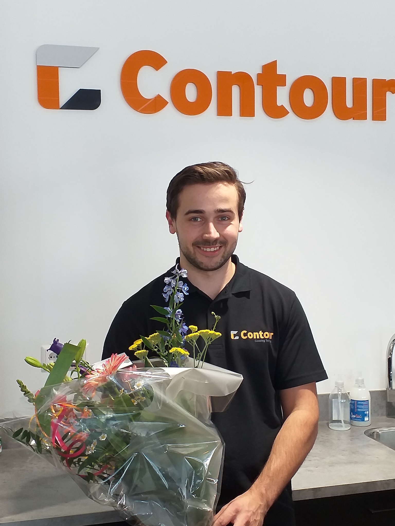 New colleague Bouke with a bouquet of flowers in front of the Contour logo