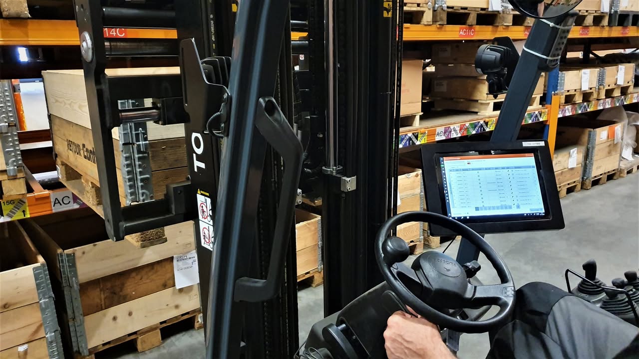 Tablet in een heftruck met de lijst van boekingen, tussen de magazijnstellingen