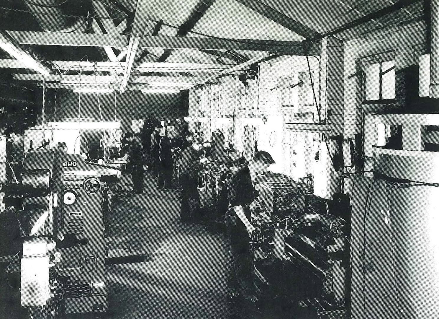 Zwart-witfoto van medewerkers aan machines in de oude productiehal