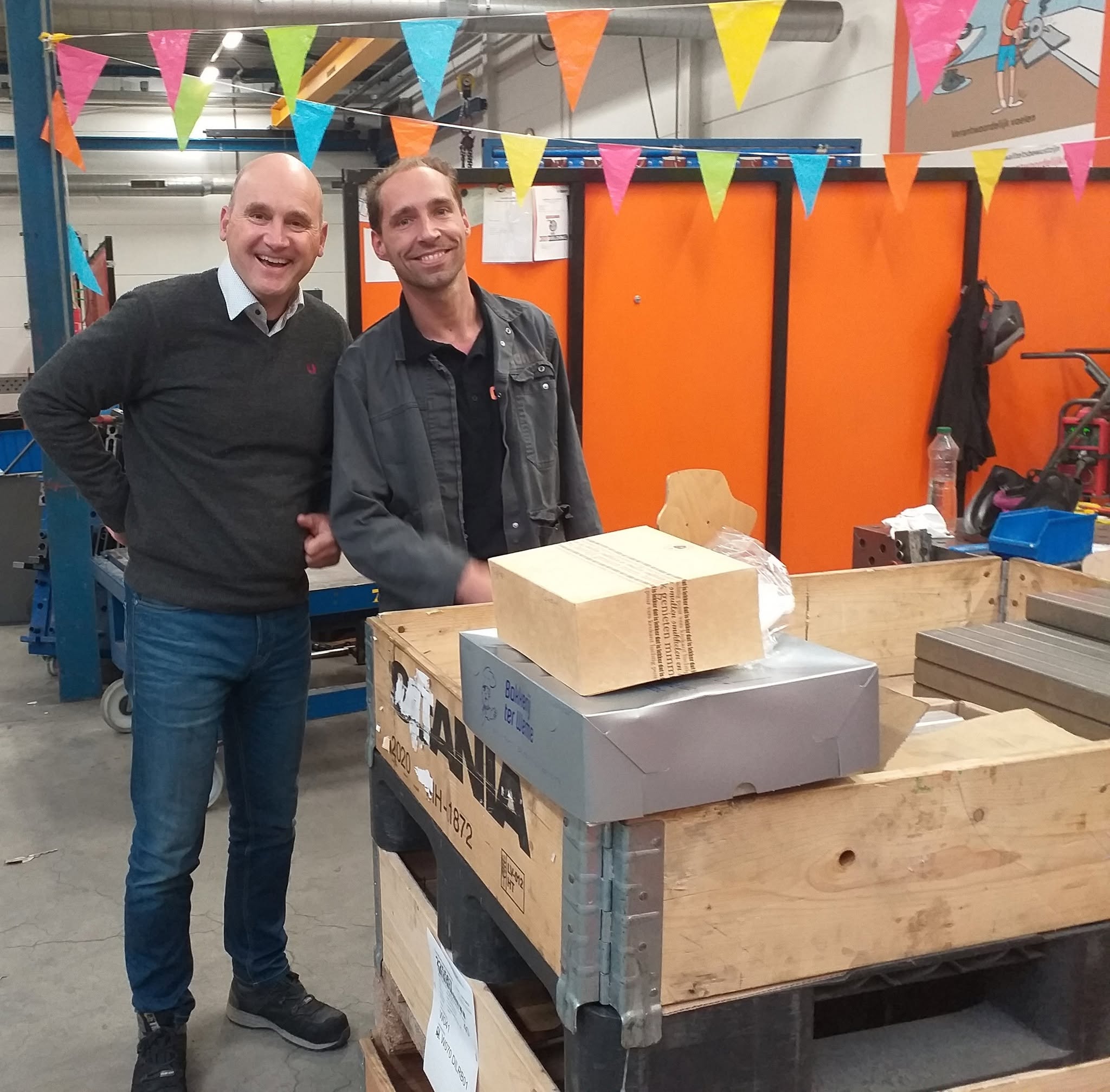 Thijs en een collega bij een pallet met gebak van Bakkerij ter Weme, tussen vlaggetjes